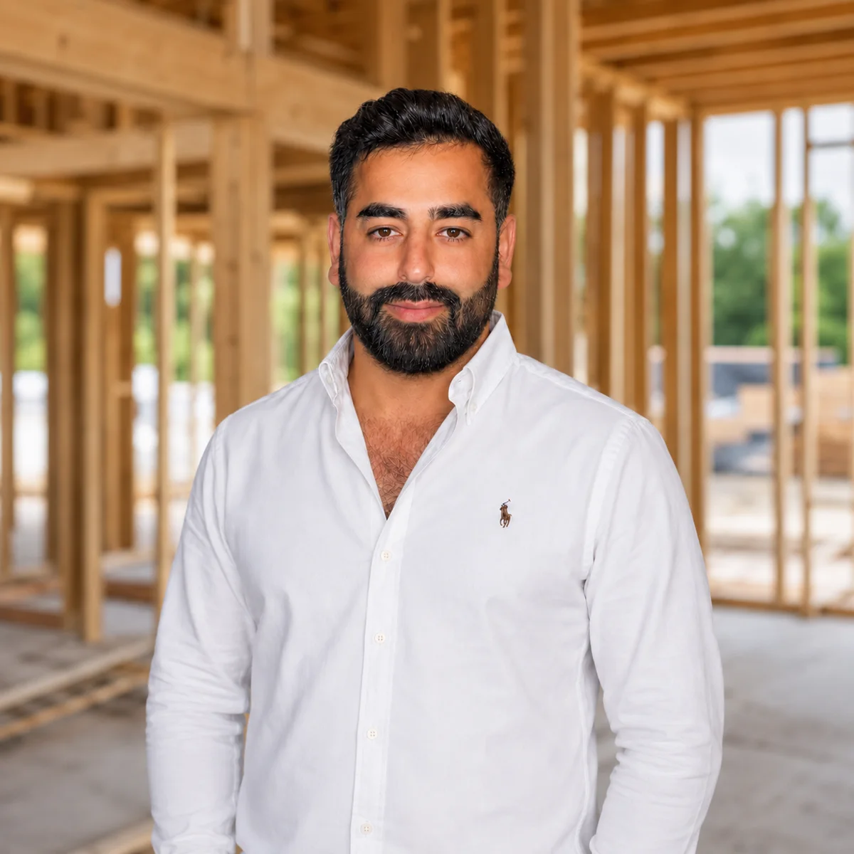 Liel Salman, founder of Excellent Builders Group, standing inside a house in framing