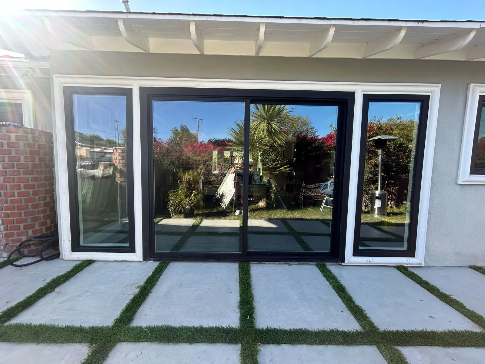 Black sliding doors opening to a paver and grass patio