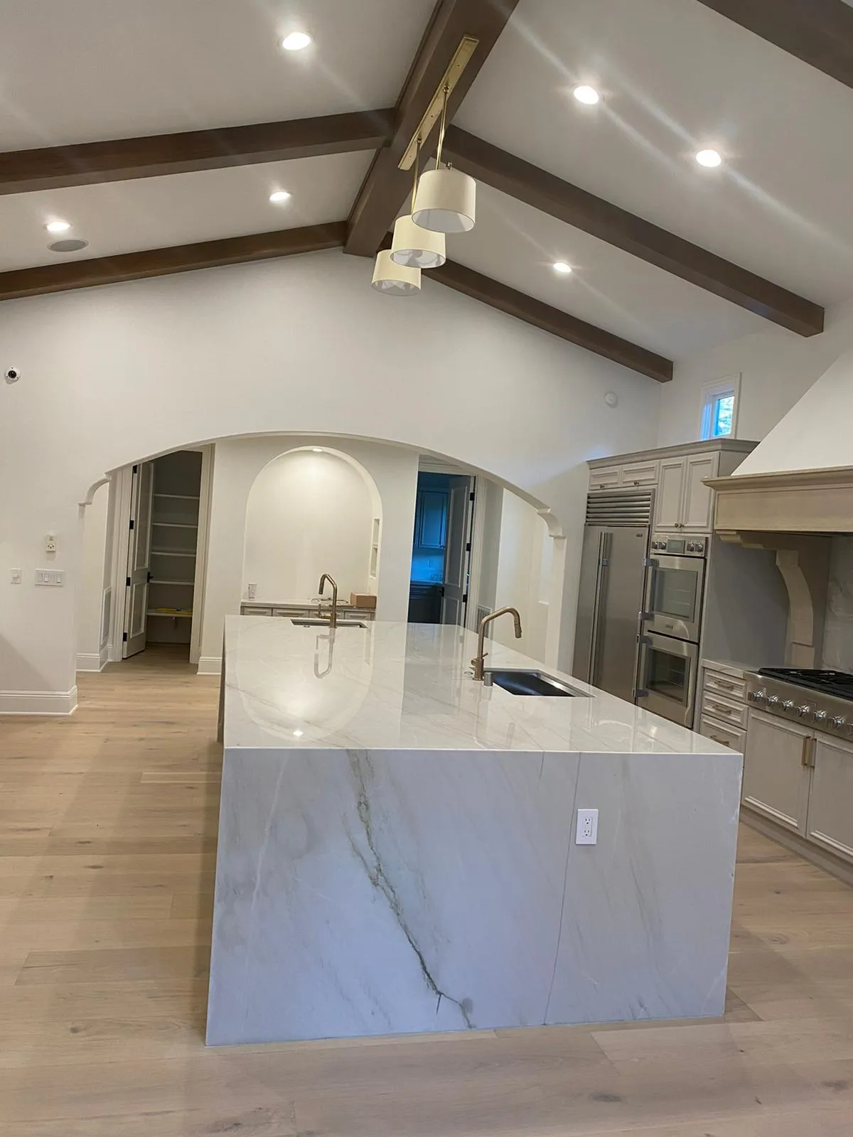 Marble waterfall island under vaulted beamed ceiling