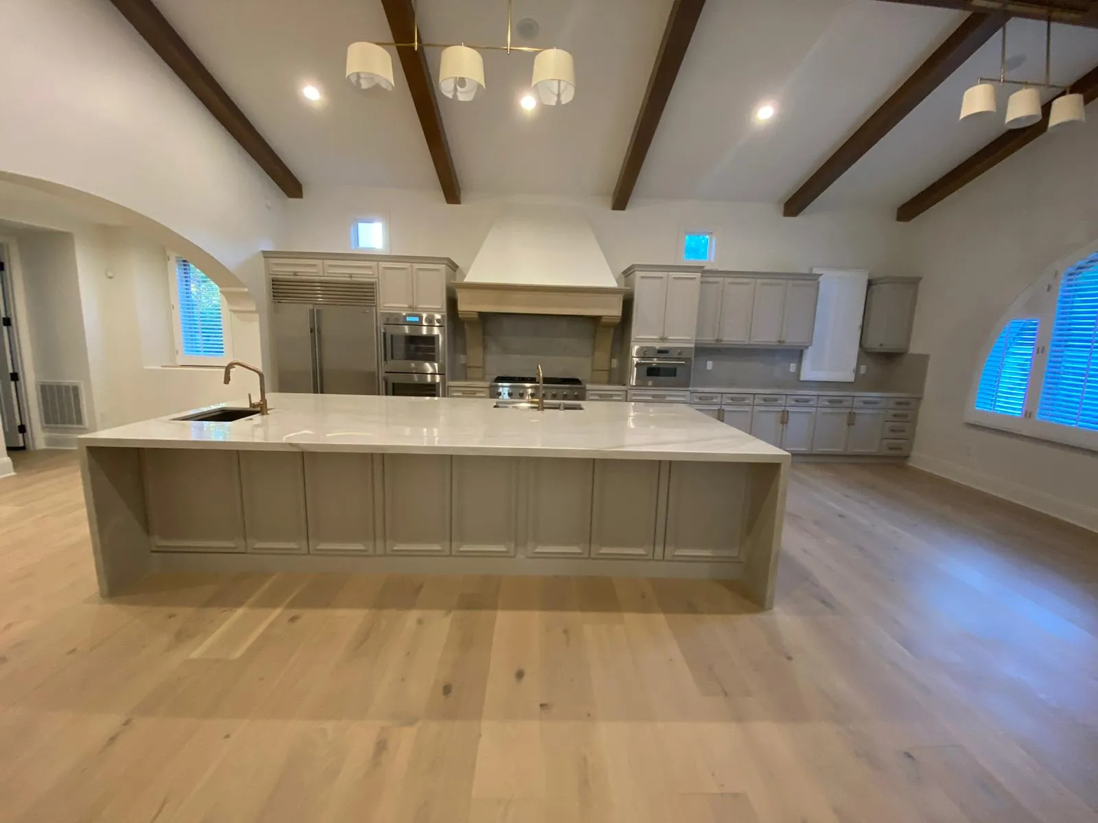 Beamed great room with kitchen island and arched openings