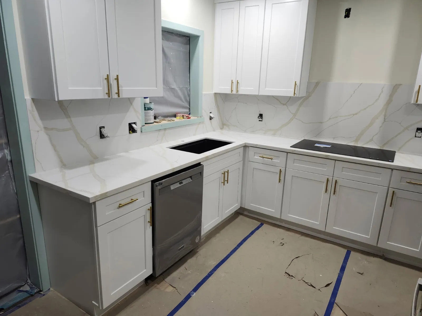 White shaker kitchen with quartz counters and new cooktop