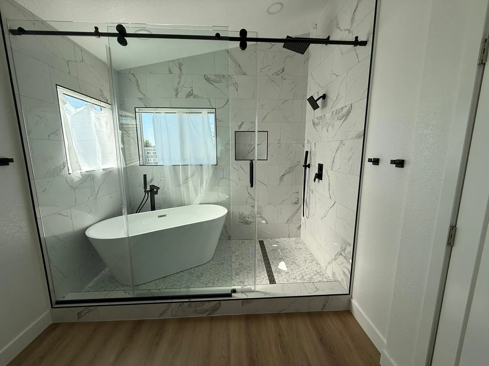 Glass shower and freestanding tub in finished marble bathroom