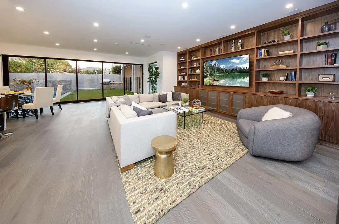 Living room with walnut built-in media wall and glass slider to the yard