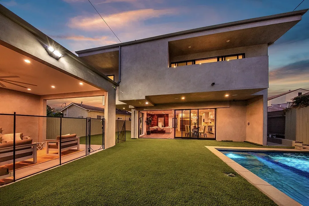 Backyard of the Sherbourne House at night with pool, turf lawn and covered patio